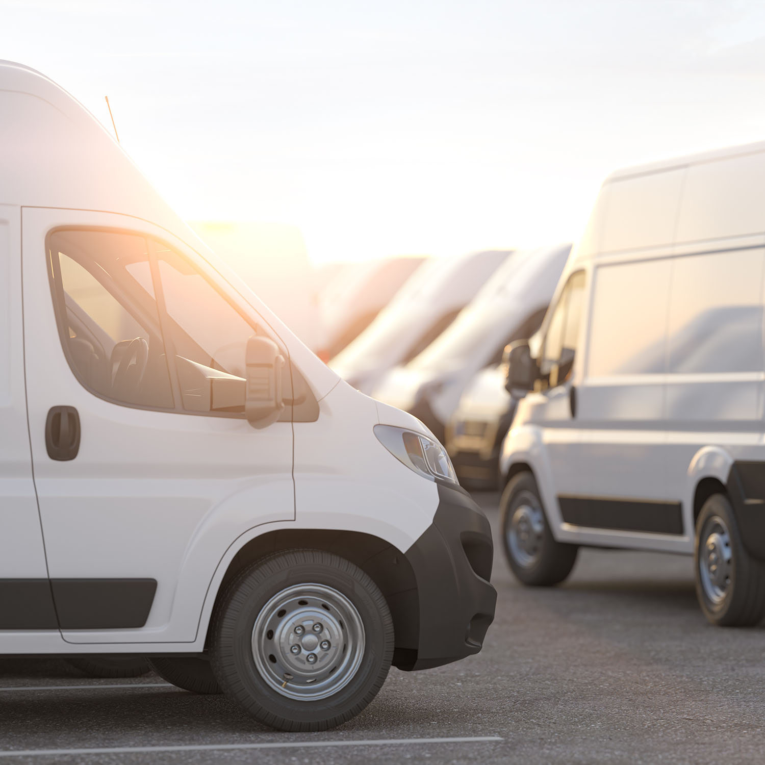 A fleet of white vans parked in a car park with a single white van front in focus.